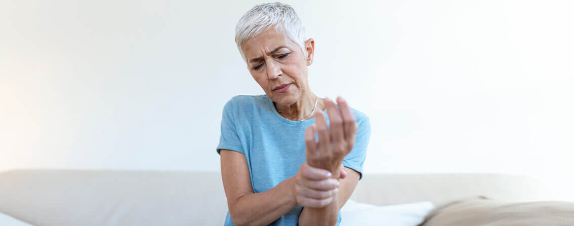 Older woman grabbing her wrist in pain.