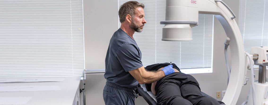 Doctor examining a patient's lower back using medical equipment and advanced technologies.
