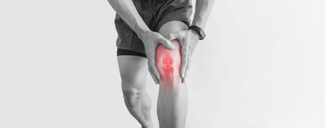 Athletic man holding his knee lit up in red due to pain.